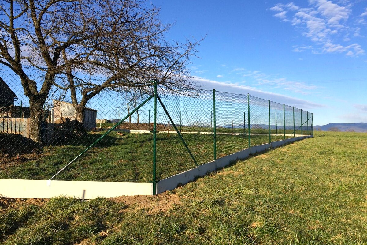 Pletivový plot s podhrabovou deskou v krajině — realizace Stavíme ploty